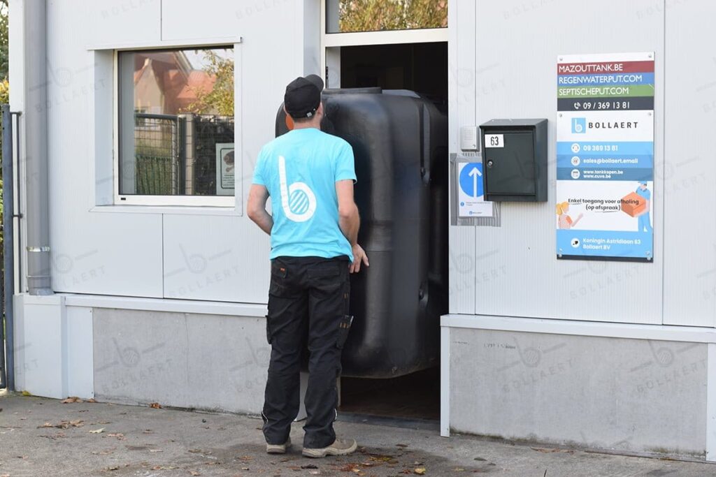 Een technieker manoeuvreert een compacte bovengrondse vetafscheider door een smalle deuropening voor plaatsing in een technische ruimte.